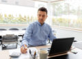 remote job, business and people concept - middle-aged man with calculator, papers and laptop computer working at home office